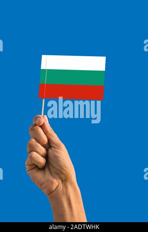 Frau hand Bulgarien Flagge mit Stick, wehende Flagge auf tief blauen Himmel. Die nationalen Thema, tief blauen Himmel. Stockfoto