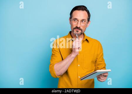 Porträt von Ernst konzentriert man Aufsatz in seiner Kopie Buch denken Gedanken schreiben betrachten, tragen moderne Kleidung über blaue Farbe Hintergrund isoliert Stockfoto