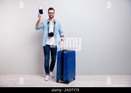 Volle Länge Foto von hübscher Kerl grosse touristische Beutel Air Tickets Dokumente traveler professioneller Fotograf Verschleiß specs Jeans Outfit isoliert Stockfoto