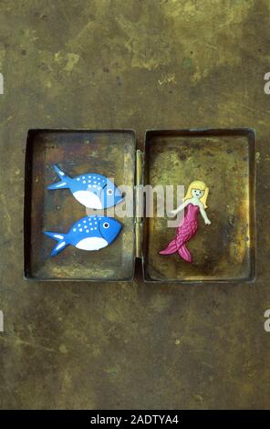 Modell der Meerjungfrau mit rosa Körper aus Messing, und wird von zwei blauen und weißen Fisch gesehen Stockfoto