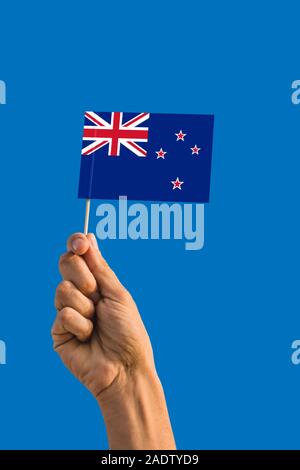 Frau hand Neuseeland Flagge mit Stick, wehende Flagge auf tief blauen Himmel. Die nationalen Thema, tief blauen Himmel. Stockfoto