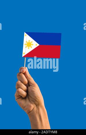 Frau hand Philippinen Fahne mit Stock, wehende Flagge auf tief blauen Himmel. Die nationalen Thema, tief blauen Himmel. Stockfoto