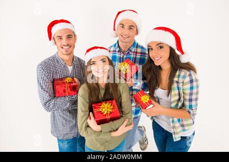 Gerne Freunde in santa Hüte holding Weihnachtsgeschenke Stockfoto