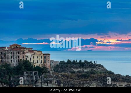 Sonnenuntergang mit Sonne in Cloud nur über Horizont in Tropea mit Panarea im Hintergrund Stockfoto