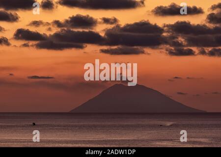 Stromboli bei Sonnenuntergang mit Rauch aus Krater auf lange Sicht über das Wasser Stockfoto