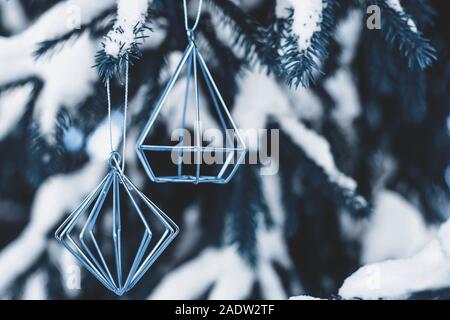 In Blau Zweige der Weihnachtsbaum mit Schnee im Freien mit Metall minimalistischen Figuren geschmückt sind getönt. Stockfoto