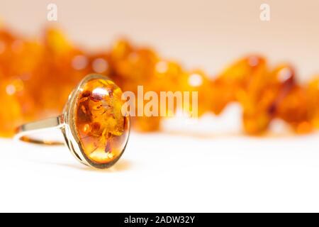 Bernsteinschmuck wie Halskette, Armband und Ring mit Edelmetall wie Gold. warm weißen Hintergrund mit Copyspace Stockfoto