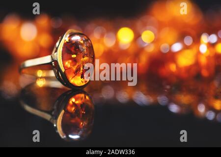 Schmuck mit Bernstein Steine, Bernstein Halskette Ring und Ohrringe und Anhänger mit Edelmetall wie Gold, vor einem schwarzen Hintergrund auf einen schwarzen Stein wit Stockfoto