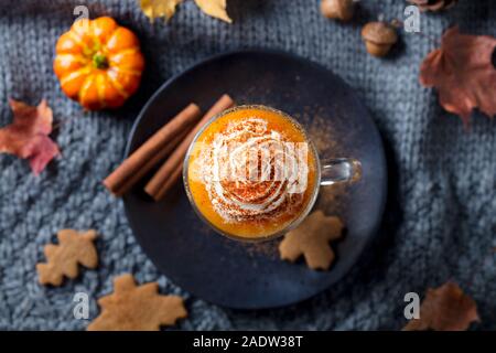 Kürbis Latte mit Gewürzen. Versoffenes Cocktail mit Schlagsahne. Grauer Hintergrund. Ansicht von oben. Nahaufnahme Stockfoto
