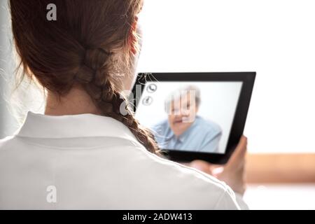 Der Arzt Rücksprache mit Telemedizin oder Telehealth, ältere Frau auf dem Display eine Tablette, Copyspace Stockfoto