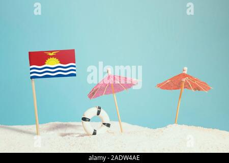 Miniatur Flagge Kiribati am Strand mit bunten Sonnenschirmen und Schwimmweste. Travel Concept, Sommer Thema. Stockfoto