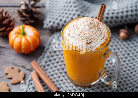 Kürbis Latte mit Gewürzen. Versoffenes Cocktail mit Schlagsahne. Holz- Hintergrund. Nahaufnahme Stockfoto