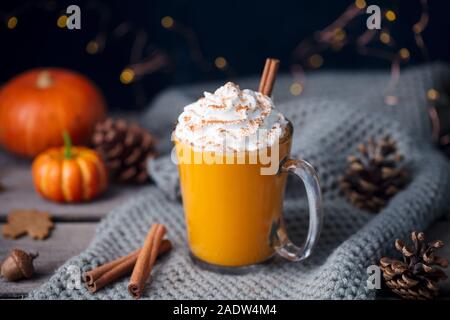 Kürbis Latte mit Gewürzen. Versoffenes Cocktail mit Schlagsahne oben auf grauem Hintergrund Stockfoto