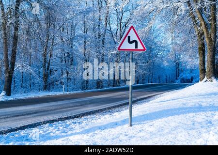 Winter fahren Konzept-Curvy winter Straße mit Warnschild Stockfoto