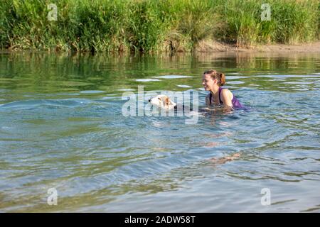 Junge Frau und Hund schwimmen in einen Fluss, Lernen und Ausbildung in Wasser Stockfoto