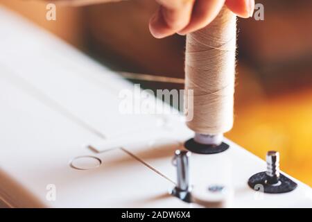 Nahaufnahme der Gewinde an der Spitze einer Nähmaschine, weibliche Hand ist mit Arbeiten Stockfoto