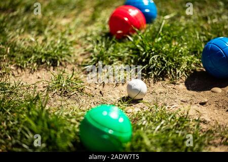 Viele bunte Kunststoff Boule oder Boccia Kugeln liegen auf der grünen Wiese im Sommer Stockfoto