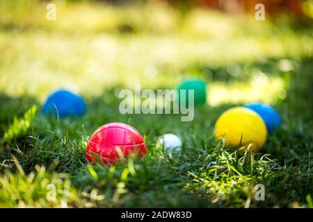 Viele bunte Kunststoff Boule oder Boccia Kugeln liegen auf der grünen Wiese im Sommer Stockfoto