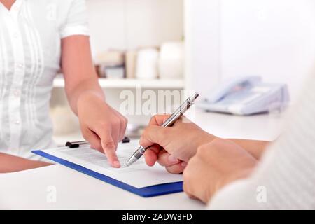 Weibliche Patienten ist die Unterzeichnung einige Dokumente in einem medizinischen Büro Stockfoto