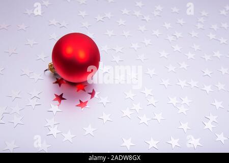 Urlaub Hintergrund mit kleinen silbernen Sterne und rote Christmas Ball auf silbernem Hintergrund. Festliche Kulisse. Stockfoto