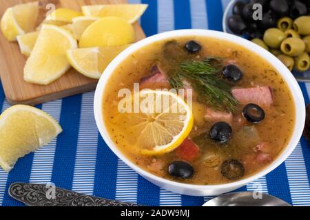 Suppe mit Fleisch, Oliven, Zitrone, Gewürze und Gewürzen auf Farbe blau Hintergrund. Russische Solyanka, hausgemachte Speisen. Ansicht von oben. Stockfoto