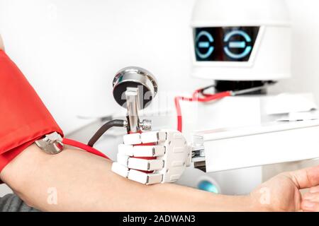 Medizinische Hilfe Roboter ist Kontrolle der Blutdruck eines männlichen Patienten, während mit einem Stethoskop Stockfoto