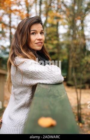 Attraktive Frau, entspannt in einem Park im Herbst umgeben von bunten Blättern auf den Bäumen nachdenklich. Stockfoto