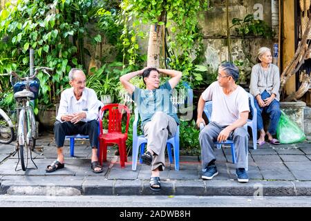 Vietnamesische Familie auf kleinen Stühlen außerhalb des Shops in Hoi An, Vietnam sitzen Ann Stockfoto