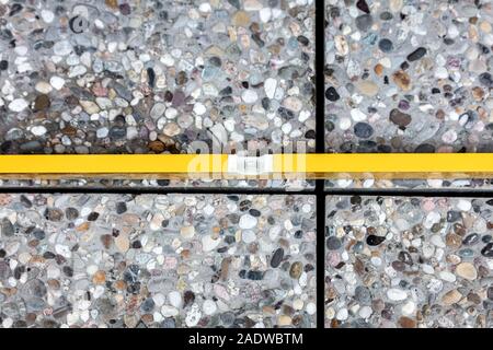 Handwerker steuert, ob frisch gelegte Bodenfliesen sind im Wasser, Wasserwaage auf waschbeton Platten Stockfoto