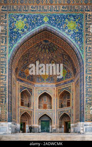 Mann in Schwarz Verschleiß tritt Tilya-Kori madrasah in historischen Registan Platz, Samarkand, Usbekistan Stockfoto