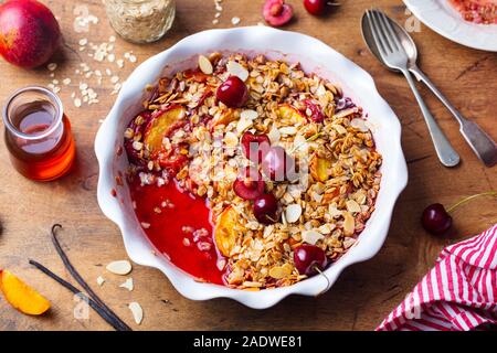 Pfirsich und Kirsche in einer Auflaufform bröckeln. Close Up. Stockfoto