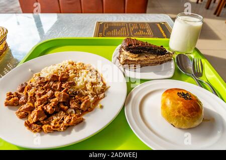 Köstliche traditionelle Tadschikistan Mittagessen mit Rindfleisch, Reis, Kuchen und Brötchen auf weißem Teller serviert Stockfoto