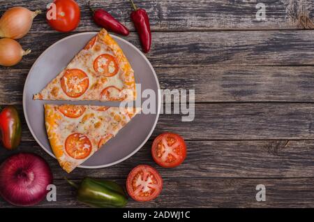 In Scheiben geschnitten ​​Pizza mit Käse und Tomaten auf eine graue Platte mit Zutaten auf einem dunklen Hintergrund mit kopieren. Für Menüs und Werbung pizzer Stockfoto