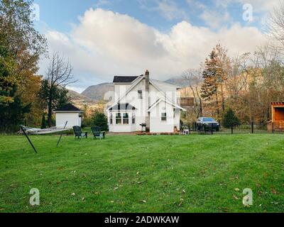 Hof Blick auf den grünen Rasen und Haus mit Blick auf die Berge im Herbst Stockfoto