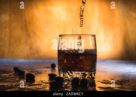 Spritzer von kaltem Eis in Glas Whiskey auf hellem Hintergrund isoliert Stockfoto