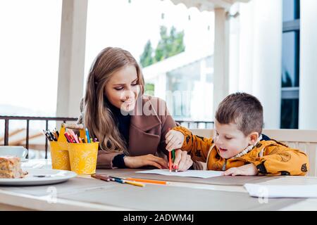 Frau lehrt den Jungen mit Buntstiften zu zeichnen Stockfoto