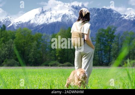 Wandern Frau mit ihrem Hund und Rucksack bei Schnee suchen, schneebedeckten Berg in der Schweiz. Stockfoto