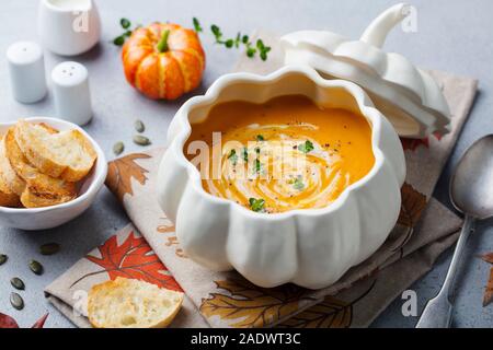 Kürbis und Karotten Cremesuppe in kreativen Schüssel. Grauer Hintergrund. Nahaufnahme Stockfoto