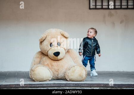 Ein kleiner Junge spielt mit einem riesigen Teddybären. Stockfoto