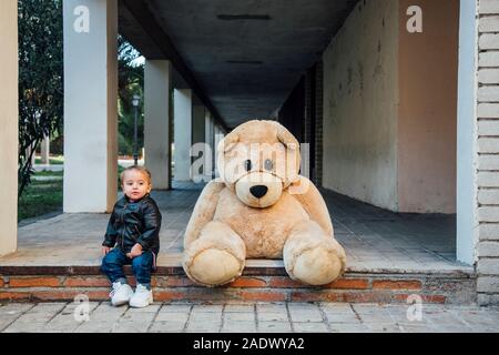 Ein kleiner Junge spielt mit einem riesigen Teddybären. Stockfoto