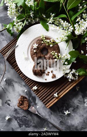 Köstliche Schokolade Kuchen und white bird cherry Blumen auf Eiche board Ansicht von oben Stockfoto