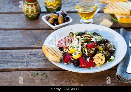 Gegrilltes Gemüse Salat mit Feta Käse in weiße Platte. Holz- Hintergrund. Platz kopieren Stockfoto