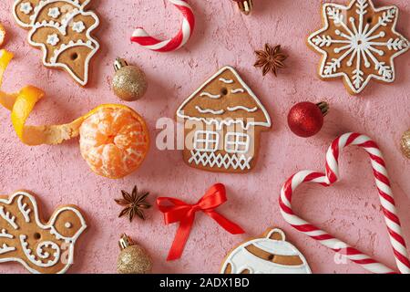 Flach Komposition mit leckere hausgemachte Weihnachtsplätzchen, Mandarin, Süßigkeiten auf rosa Hintergrund. Ansicht von oben Stockfoto