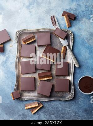 Schokolade Karamell Schichten, Bars, Millionäre shortbread auf einem vintage Fach blauen Hintergrund. Ansicht von oben Stockfoto