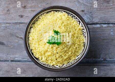 Couscous in der Schüssel. Holz- Hintergrund. Close Up. Ansicht von oben Stockfoto