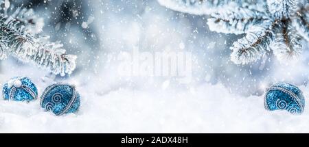 Blaue Weihnachtskugeln auf Schnee mit Tannenzweigen. Merry Xmas Konzept - Panorama banner Stockfoto