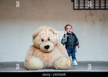 Ein kleiner Junge spielt mit einem riesigen Teddybären. Stockfoto