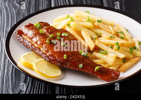 Gesundes Essen gebratener Rotbarsch Fisch mit Pommes frites Salat close-up in einem Teller auf dem Tisch. Horizontale Stockfoto