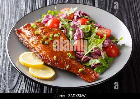 Gesundes Essen gebratener Rotbarsch Fisch mit frischem Gemüse Salat close-up in einem Teller auf dem Tisch. Horizontale Stockfoto