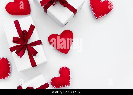 Grenze von Geschenkboxen verpackt Red Ribbon mit Filz Herzen auf weißem Hintergrund. Valentines Tag oder Tag Womans urlaub Konzept. Ansicht von oben. Stockfoto